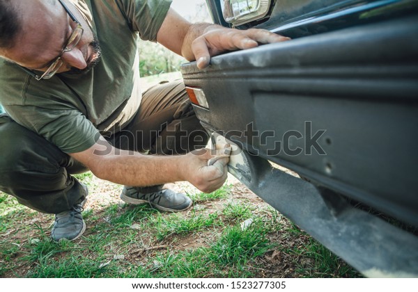 Young man preparing varnish with a sandpaper. Small\
business and painting a\
car