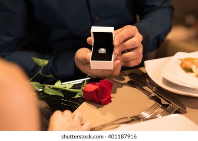 Young man presenting engagement ring to girlfriend. Husband gifting a diamond ring to wife on anniversary. Man holding box with ring making propose to girlfriend.  - Powered by Shutterstock