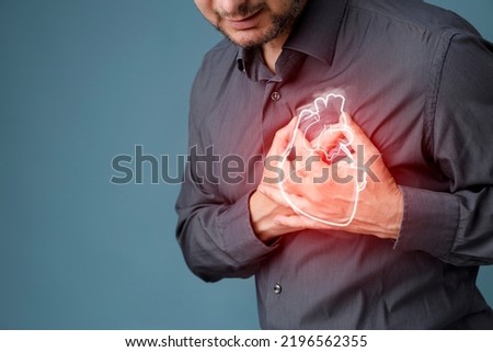 Young man pressing on chest with painful expression. Severe heartache, having heart attack or painful cramps, heart disease.