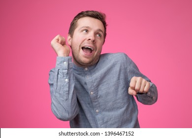 Young Man Pretends To Dance On Pink Wall. Studio Shot