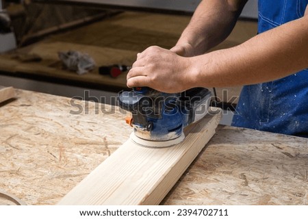 Young Man  processes the board with a random orbit sander in the workshop