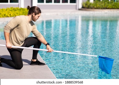 Young man professional cleaner worker cleaning pool with scoop net outdoors.