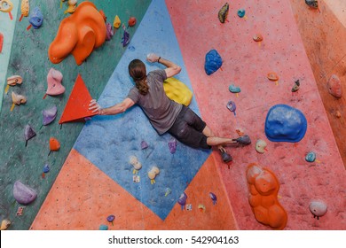 Young man professional climber exercising at indoor bouldering artificial wall - Powered by Shutterstock