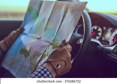 Young Man Professional Driver Looking In To The Paper Map Inside Luxury Car With Leather Interior