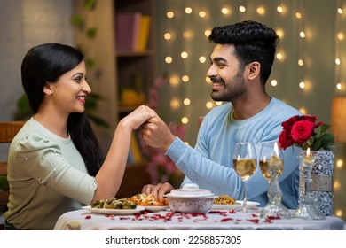 young man proposing to girlfriend by holding hands while arranging candlelight dinner - concept of love or emotion, valentine day and romantic couple - Powered by Shutterstock