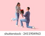 Young man proposing to his girlfriend on pink background. Valentine