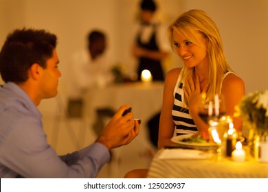 young man proposing to his girlfriend in a restaurant while having candlelight dinner