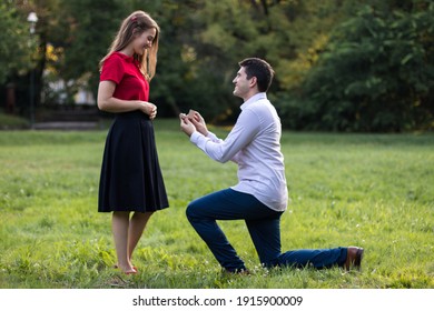 Young man proposing to his loved one, down on his knee with the ring in his hands.