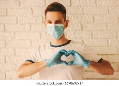 Young man in protective face mask and medical gloves on hands gesturing heart symbol. Doctor in medical face mask and protective gloves shows love symbol by fingers. Healthcare, COVID-19, coronavirus - Powered by Shutterstock