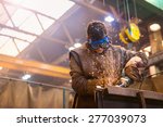 Young man with protective goggles welding in a factory