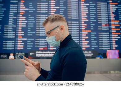 Young Man In Protective Mask Background Information Board In Airport Terminal. Concept Online Checkin For Plane.