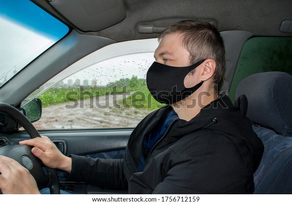 Young man in protective sterile medical mask\
driving car. Coronavirus covid-19, virus, pandemic. Virus\
protection concept.