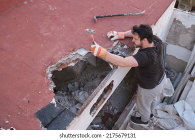 Young Man Pulling Apart The Ceiling Of A House Down Using A Mallet.