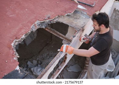 Young Man Pulling Apart The Ceiling Of A House Down Using A Mallet.