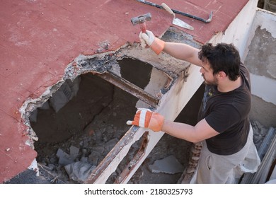 Young Man Pulling The Roof Of A House Down Using A Mallet.