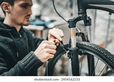 A young man pulls a brake cable on the handlebars of a bicycle.