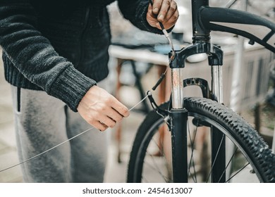 A young man pulls a brake cable on the handlebars of a bicycle.