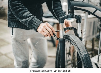 A young man pulls a brake cable on the handlebars of a bicycle. - Powered by Shutterstock