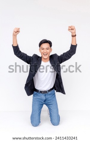 A young man pumped up and celebrating while sliding on his knees. Concept of exhilaration. Kneeling whole body shot Isolated on a white background.