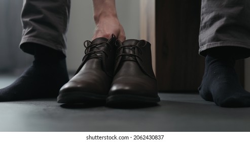 Young man put on his brown leather chukka boots indoor