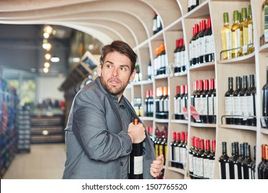 Young Man Puts A Bottle Of Wine In His Jacket During Shoplifting