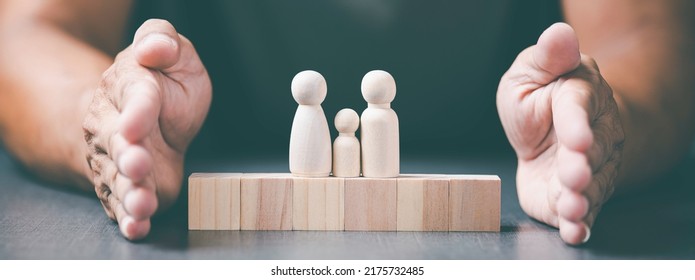 Young Man Puts His Hand Next To A Wooden Block, Care Concept, Protect, Keep Family Members Safe And Happy.