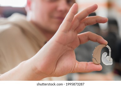 A Young Man Puts On A Hearing Aid. Portable Sound Amplifier For The Deaf And Hearing Impaired