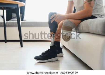 A young man puts on a prosthetic leg at home. Amputation and use of an artificial leg.