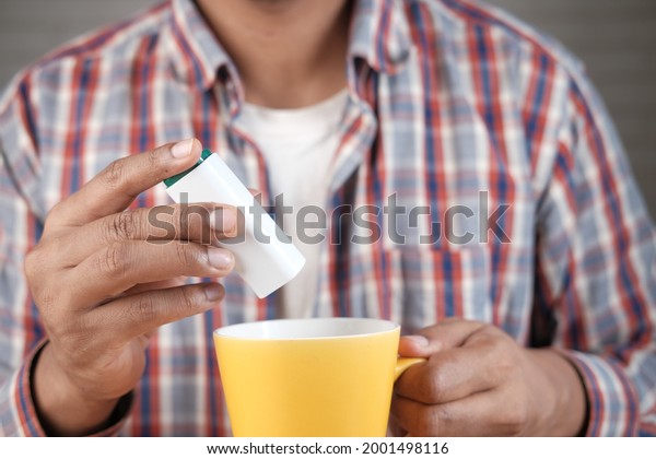 young man\
putting artificial sweetener in\
tea,