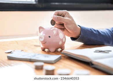 Young man putting coins into piggy bank planning growing saving to strategy with money box for future plan fund of travel, education, home and retirement. - Powered by Shutterstock