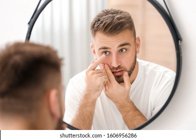 Young man putting in contact lenses near mirror - Powered by Shutterstock