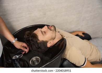 Young man putting head in barber sink for hair wash