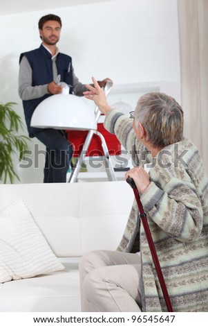 Young man putting up a light for an elderly woman