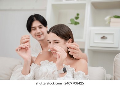 A young man putting the necklace around his girlfriend's neck in the kitchen on Valentine's Day Valentine's Day concept. Lovers at home celebrating Valentine's Day. - Powered by Shutterstock