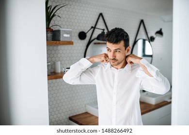 Young Man Putting On Shirt In The Bathroom In The Morning.