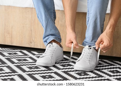 Young man putting on shoes at home - Powered by Shutterstock