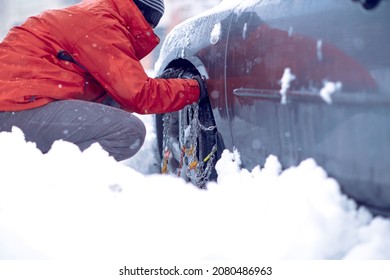 Young man putting winter chains on car.Confused man does not know how to put snow chains on car tire.