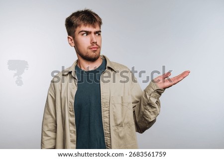 Young man with a puzzled expression holding out his hand.