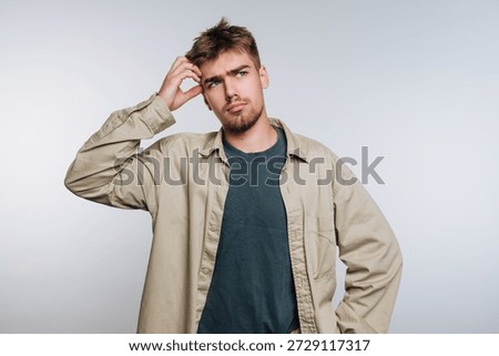 Young man with a puzzled expression scratching his head.
