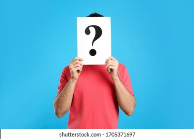 Young Man With Question Mark Sign On Light Blue Background