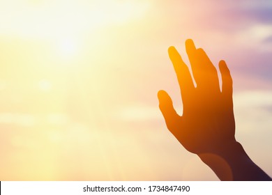 young man raising hands praying at sunset or sunrise light, dreams, freedom and spirituality concept, copy space