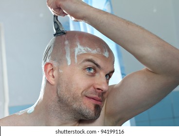 Young Man With Razor Shaving Head