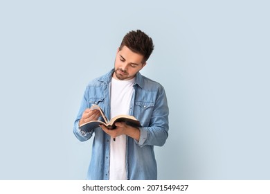 Young Man Reading Bible On Color Background