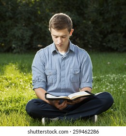 Young Man Reading Bible In A Park