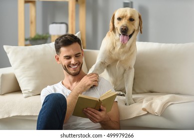 young man reading book to a dog