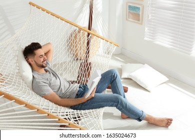 Young man reading book in hammock at home - Powered by Shutterstock