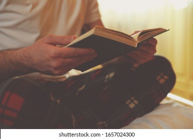 Young Man Reading Book On Bed At Home, Closeup