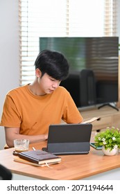 Young man reading book while sitting in living room.