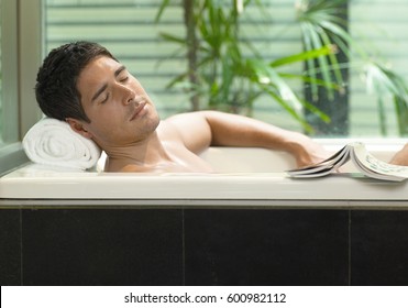 Young man reading book while lying in the bath  - Powered by Shutterstock