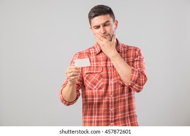 Young Man Reading Business Card Isolated On Gray Background